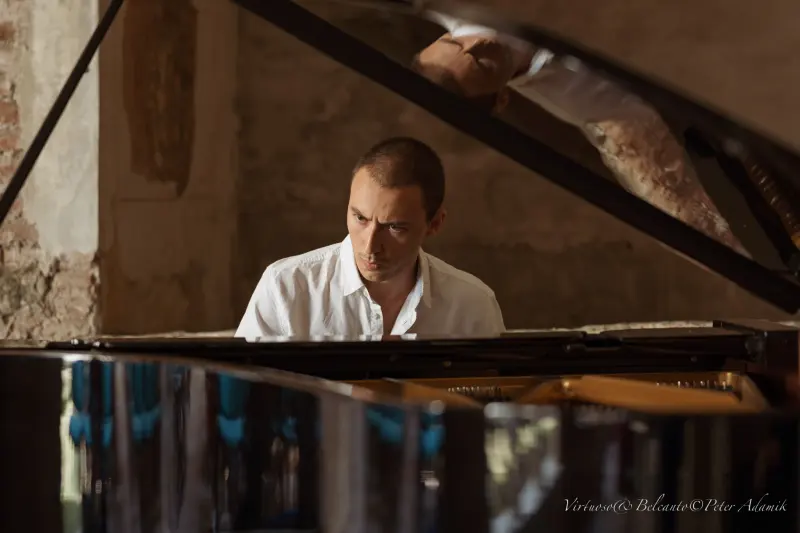 Francisco playing, seen across the open lid of a grand piano