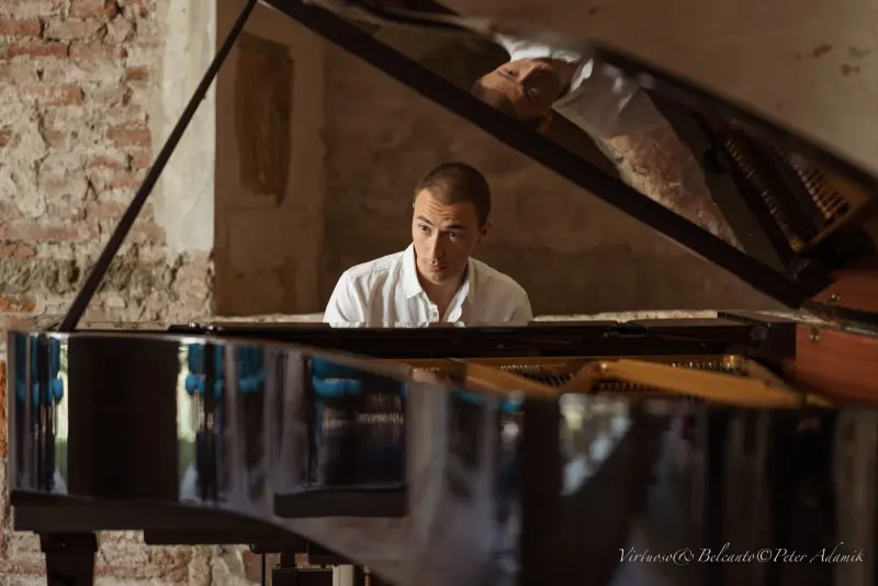 Francisco playing a grand piano in a stone-walled room