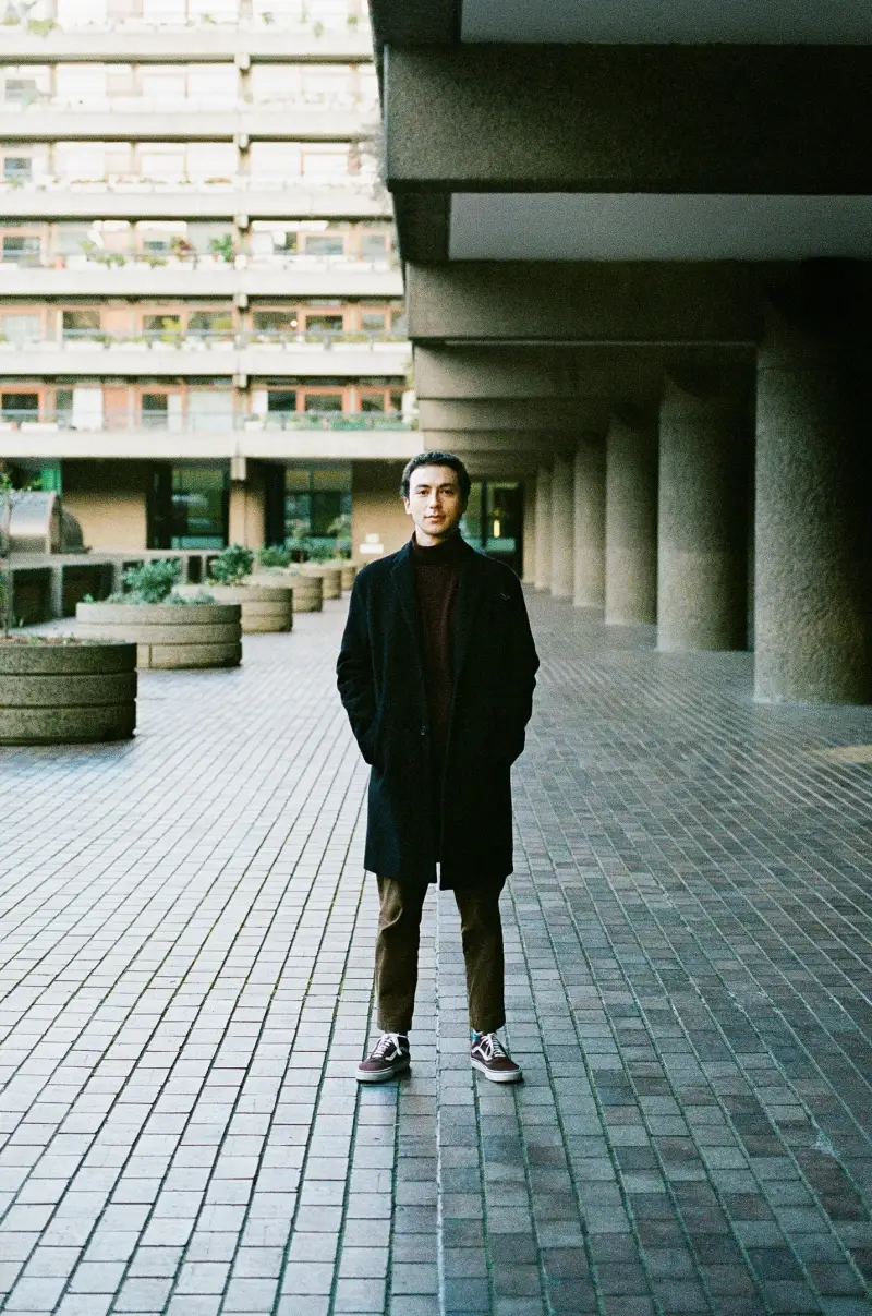 Francisco Couto standing in a long concrete walkway at the Barbican, London