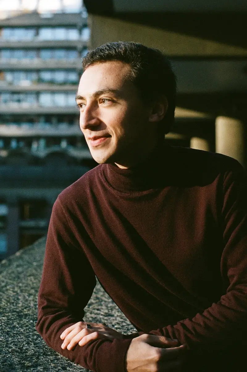 Francisco looking to the side, leaning on a concrete ledge