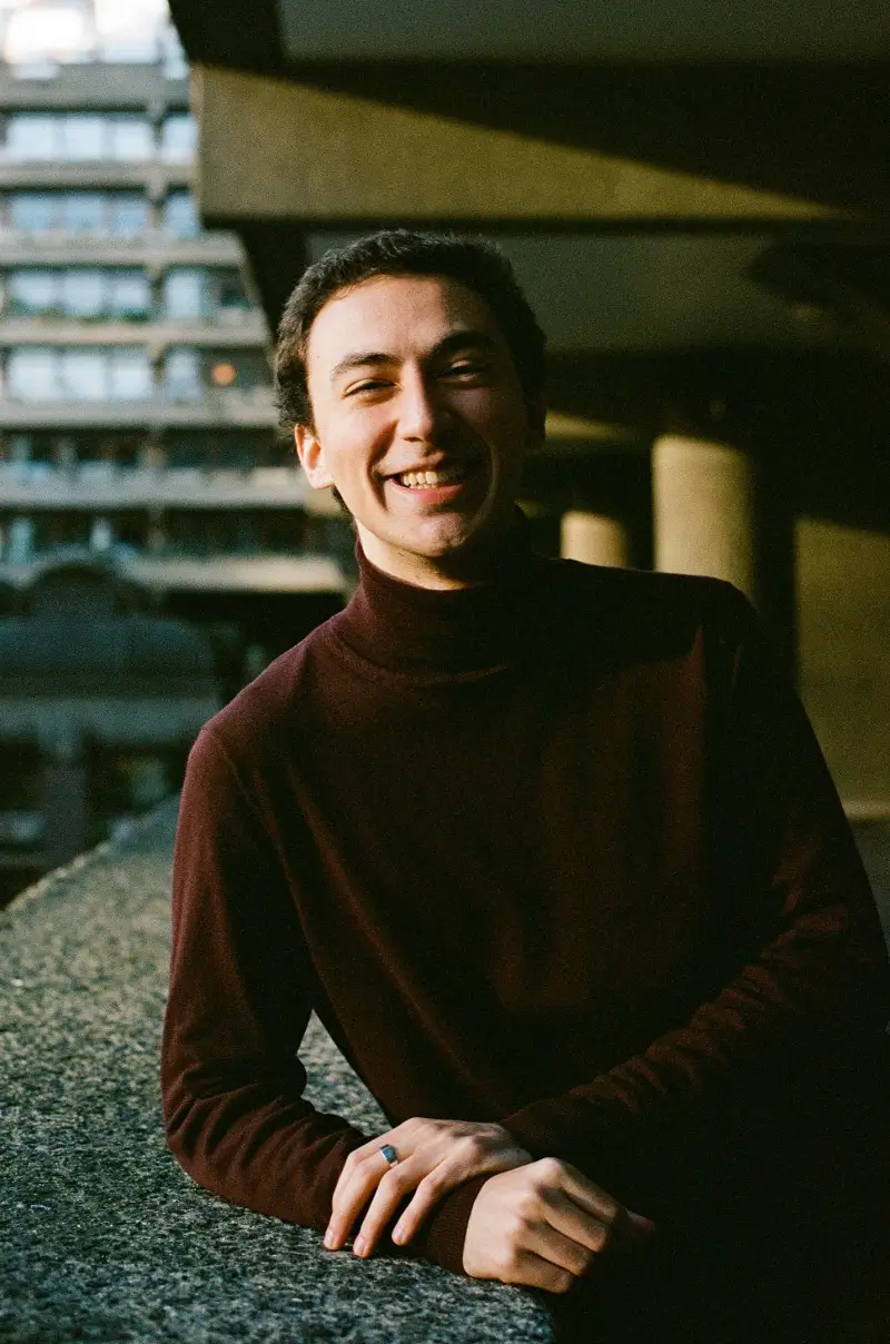 Francisco Couto smiling, leaning on a concrete ledge at the Barbican