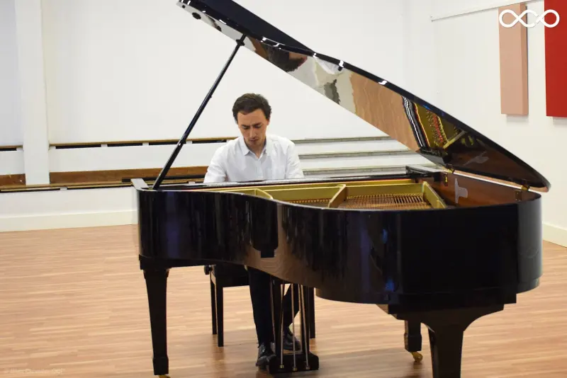 Francisco playing a grand piano in a bright recital hall